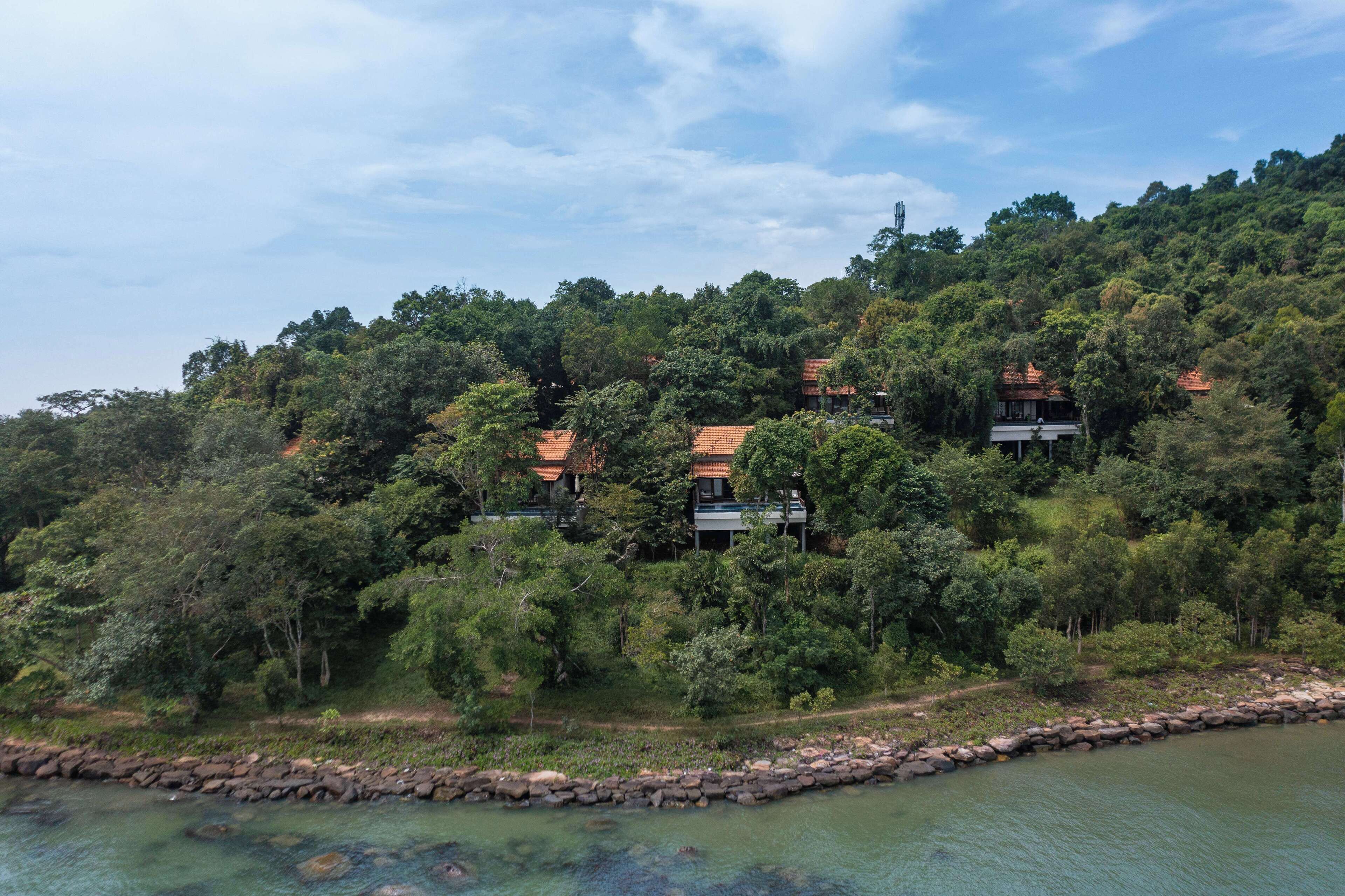 A hillside property with multiple buildings surrounded by dense forest.