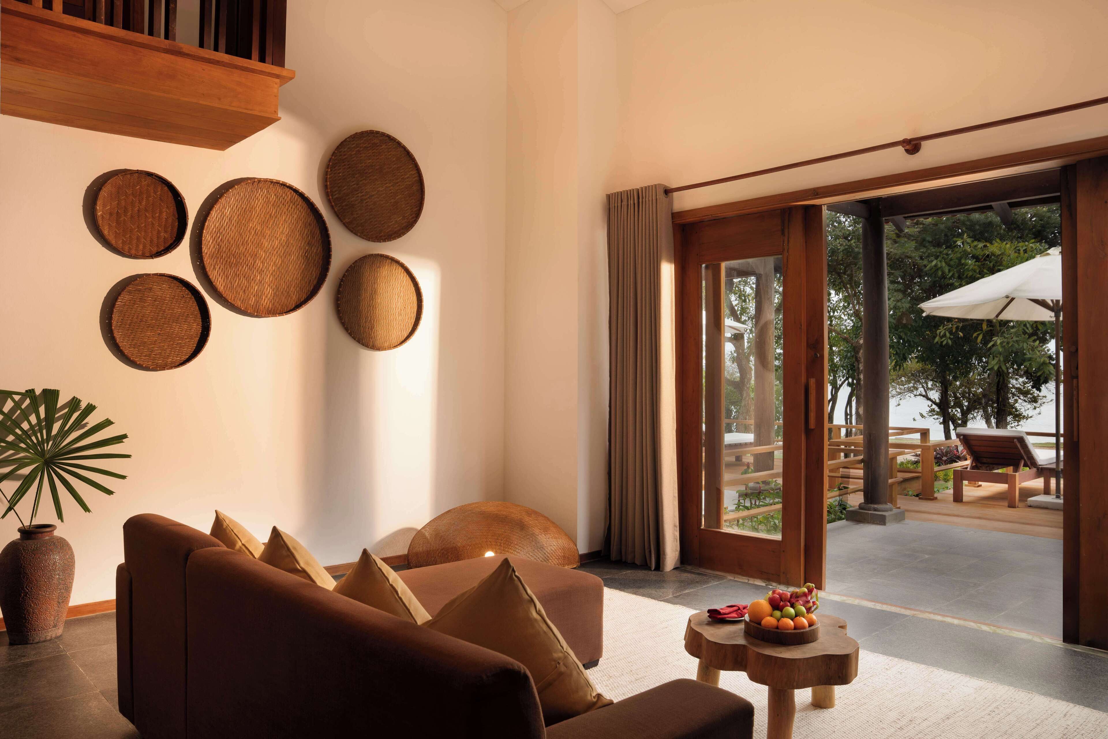 Una sala de estar moderna con un sofá, una mesita de centro con fruta y vistas a una zona de estar exterior.