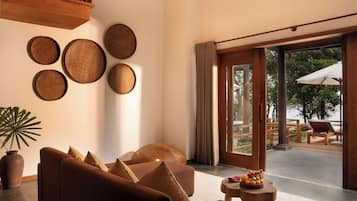 Una sala de estar moderna con un sofá, una mesita de centro con fruta y vistas a una zona de estar exterior.