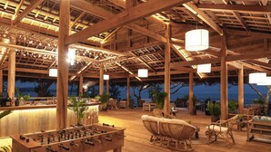 An outdoor bar area with wooden furniture, a foosball table, and hanging lights. - Green Bay Phu Quoc Resort & Spa (Phu Quoc)