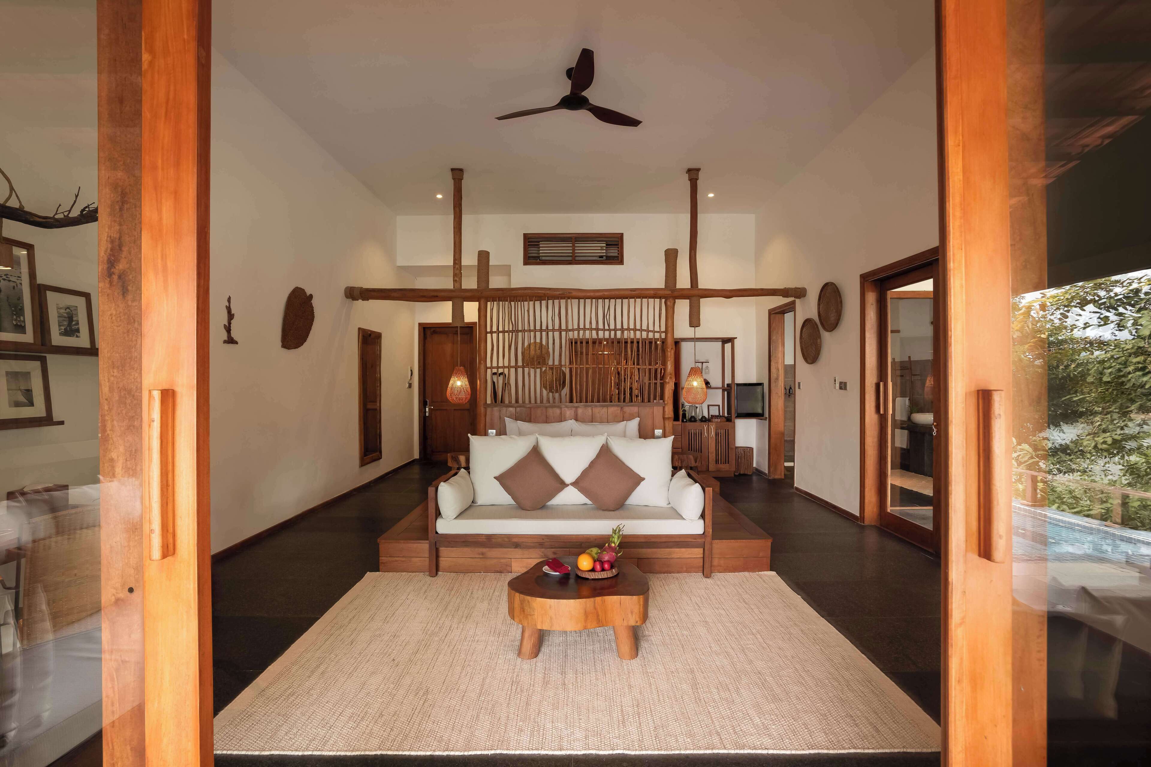 A spacious living area with a sofa, a coffee table with fruits, and a ceiling fan.