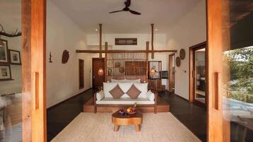 A spacious living area with a sofa, a coffee table with fruits, and a ceiling fan.