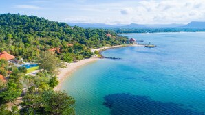 An aerial view of a coastal area with a beach, a small island, and a forested hill. - Green Bay Phu Quoc Resort & Spa (Phu Quoc)