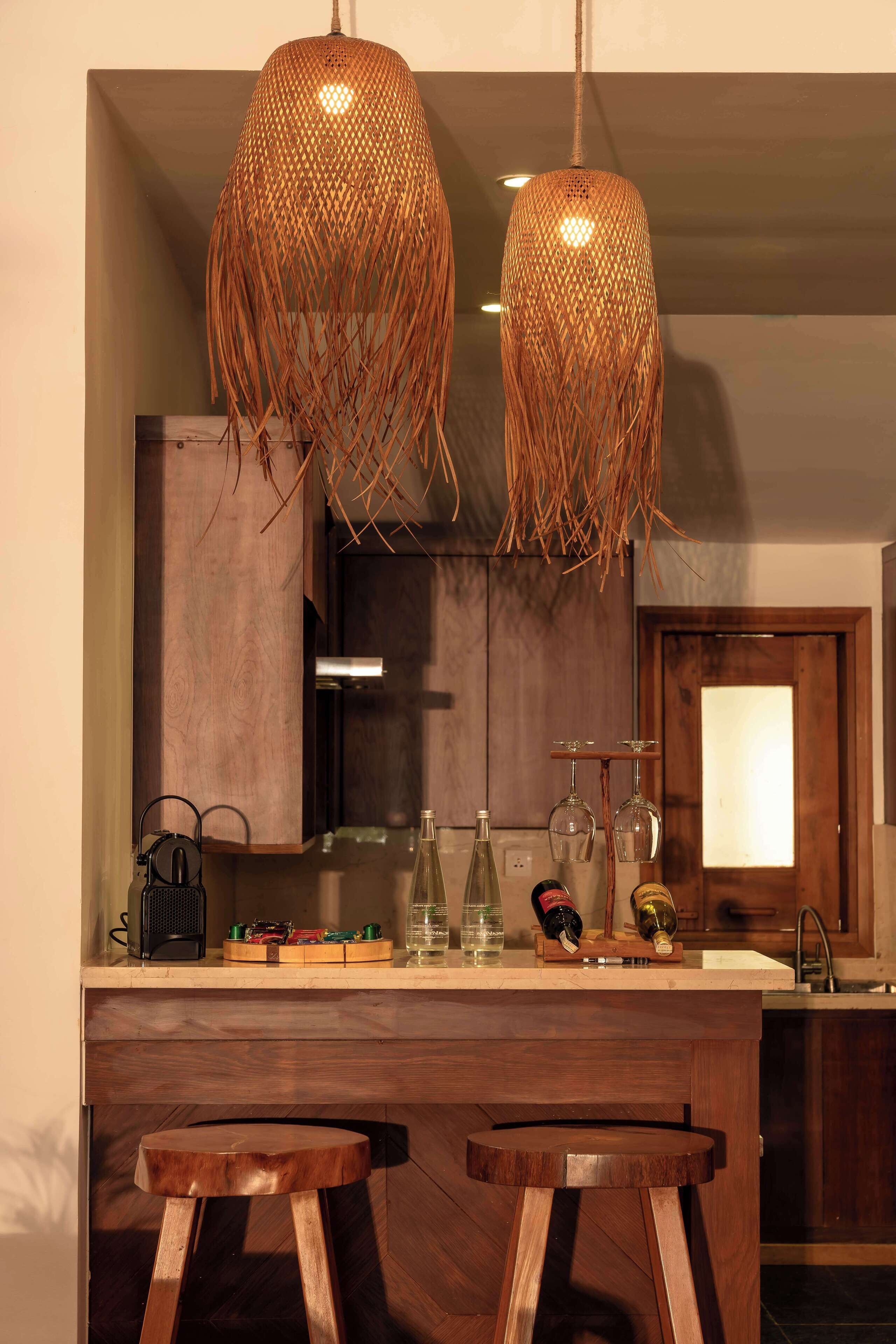 A kitchen with wooden cabinets, a bar area with stools, and two hanging woven light fixtures.