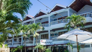 Um hotel com piscina, várias varandas e palmeiras.