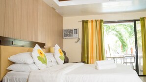 Quarto de hotel com uma cama, um ventilador de teto e janela com cortinas.