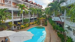 Hotel com piscina rodeada por vegetação exuberante e várias varandas.