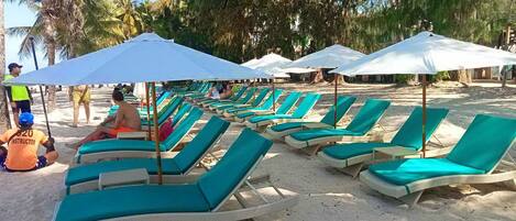 Am Strand, weißer Sandstrand, Liegestühle, Sonnenschirme