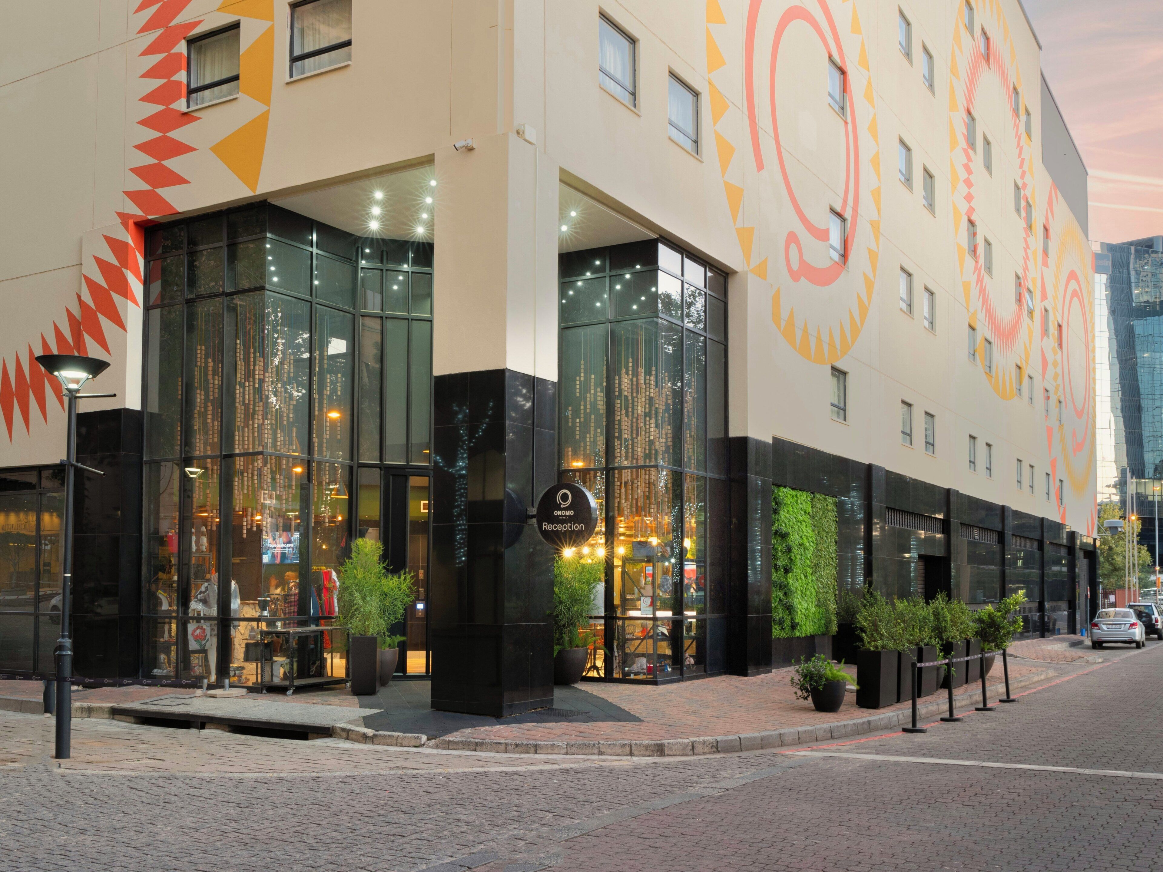 A hotel with a modern glass facade, a reception area, and a large outdoor seating area.