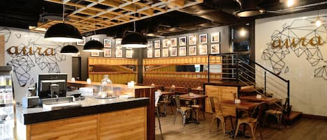 A restaurant interior with wooden furniture, a counter, and framed pictures on the walls.