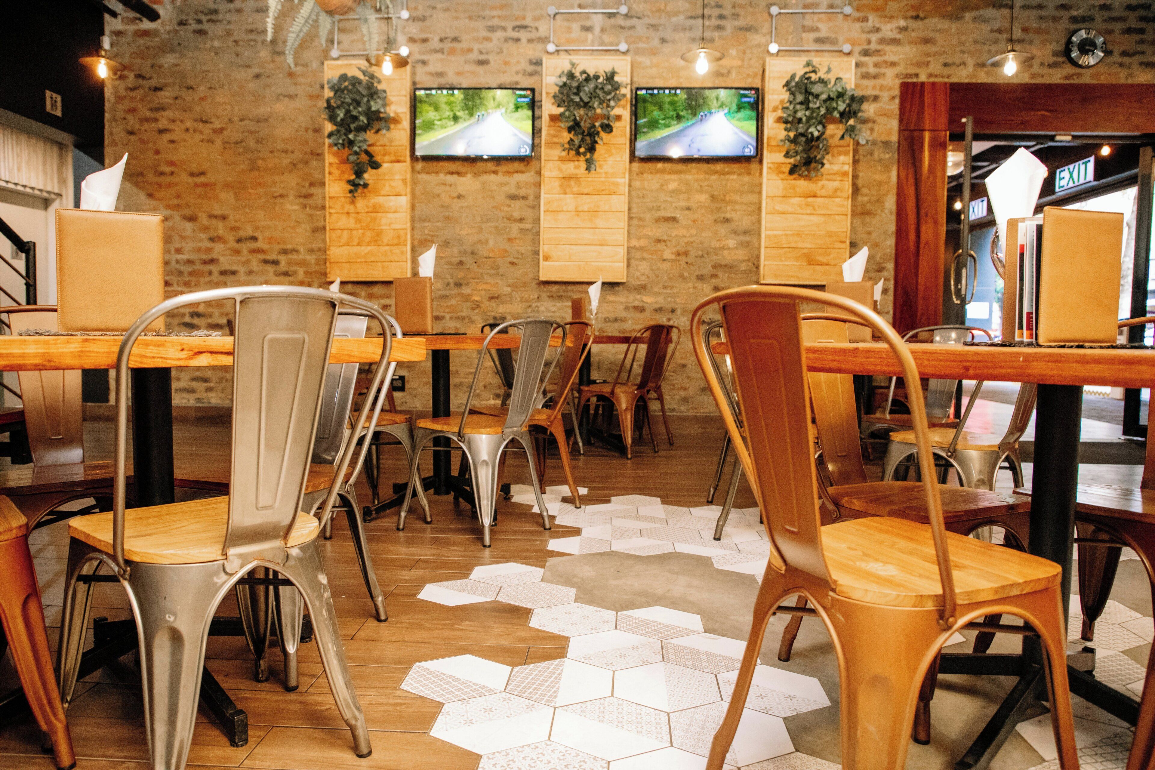 A restaurant interior with brick walls, multiple TVs mounted on the wall, and hexagonal patterned flooring.