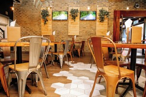 Interior de un restaurante con paredes de ladrillo, varios televisores montados y piso con patrón hexagonal.