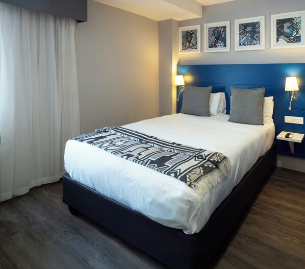Habitación de hotel con una cama grande, dos lámparas de noche y un cabecero con decoración mural.