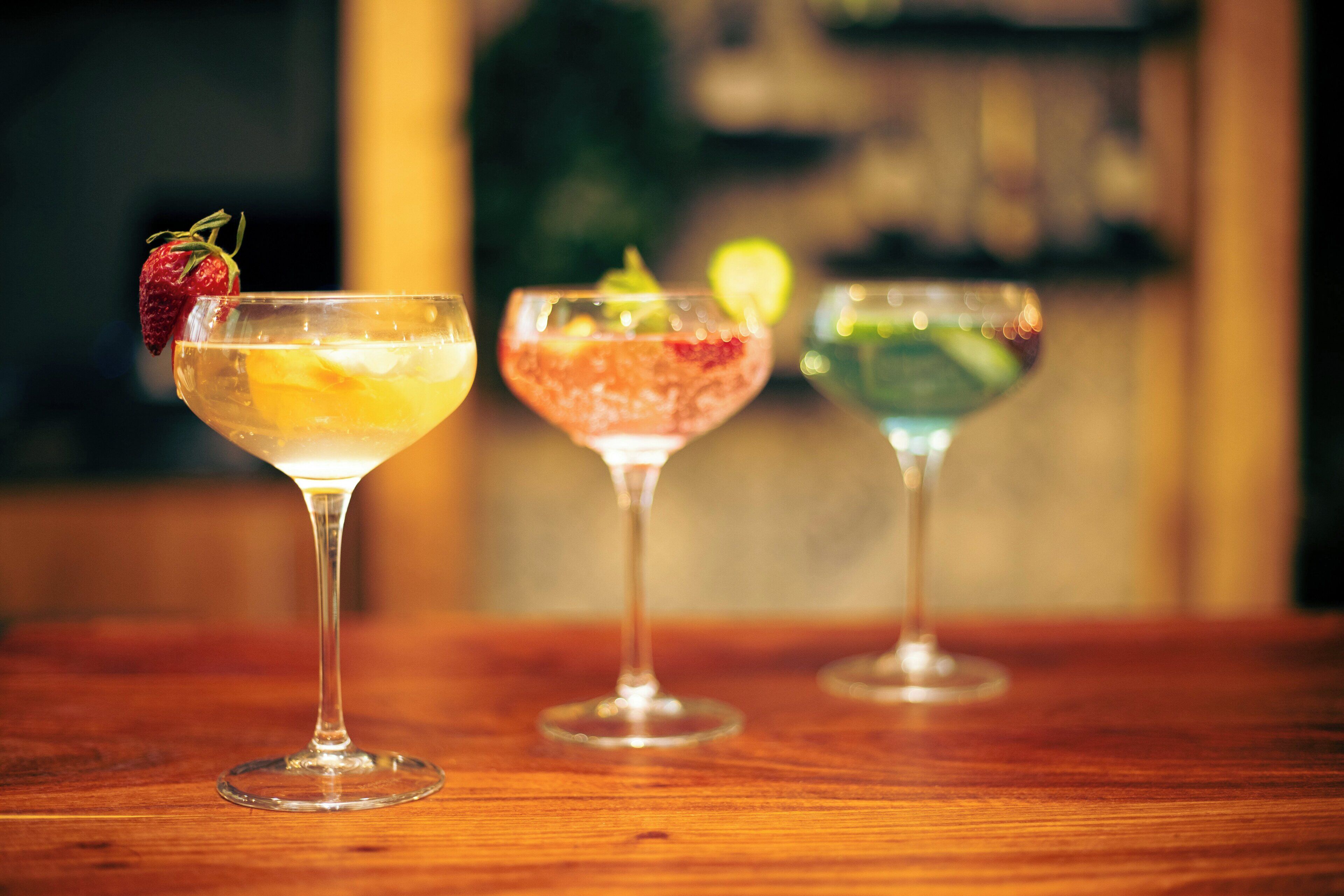 Three cocktails on a wooden table.