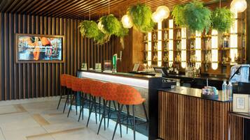 Zona de bar con techo de madera, plantas colgantes y mostrador con taburetes.