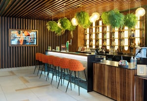 A bar area with a wooden ceiling, hanging plants, and a bar counter with stools.