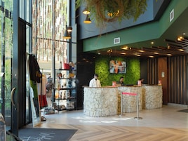 Un área de recepción con mostrador de piedra, pared verde con pantalla y techo de madera.