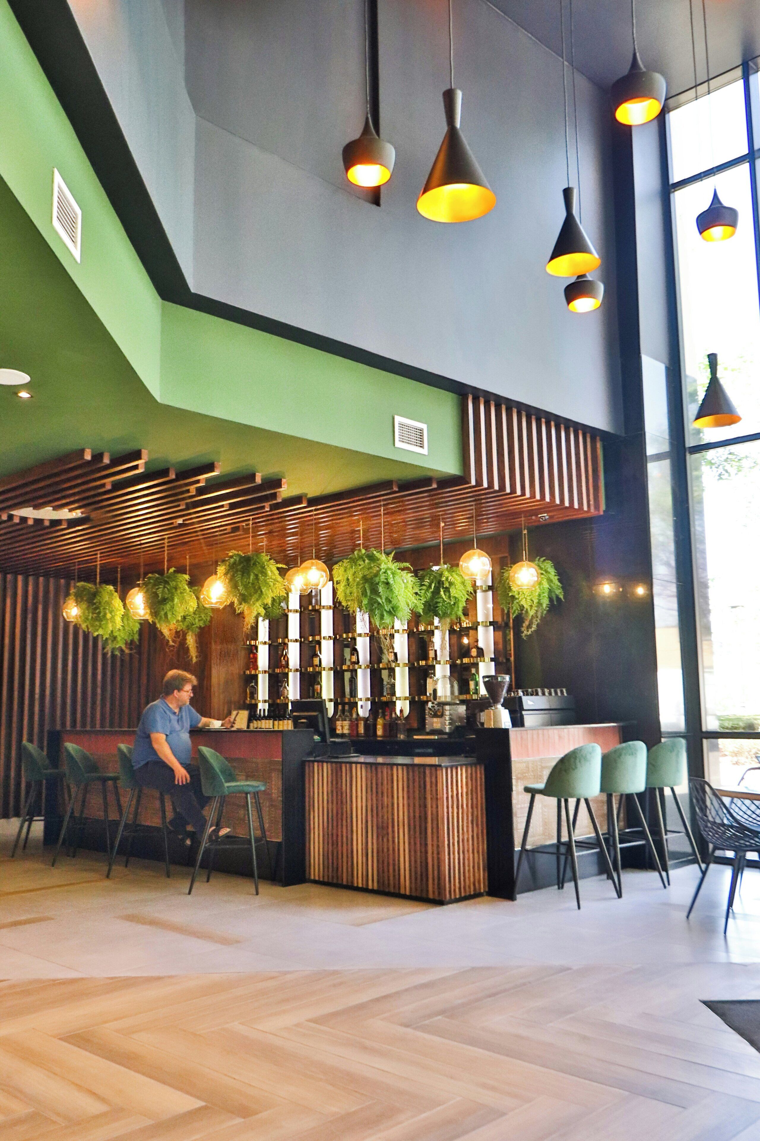 A modern interior with a bar area, seating, and hanging plants.