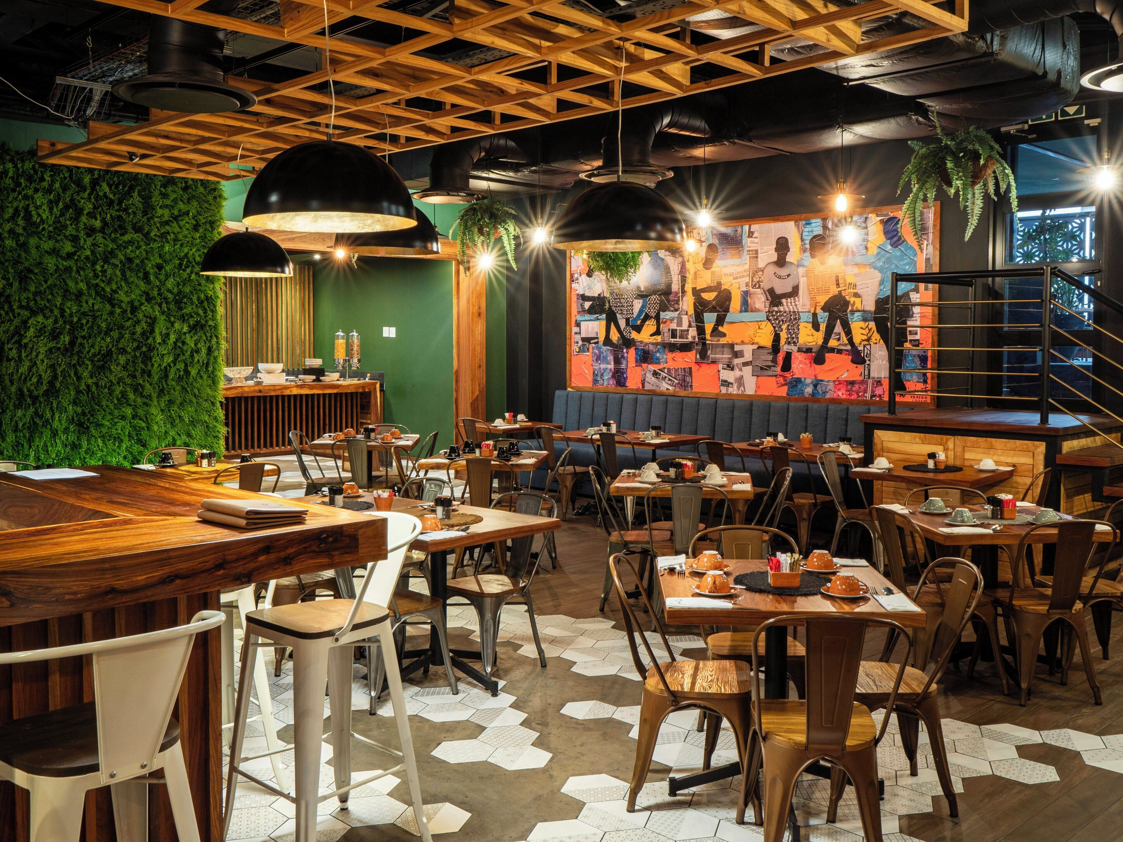 A restaurant interior with wooden tables, chairs, and a green wall.