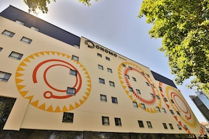 Un edificio de hotel con un logotipo circular distintivo y el nombre 'ONOMO HOTELS' en la fachada.
