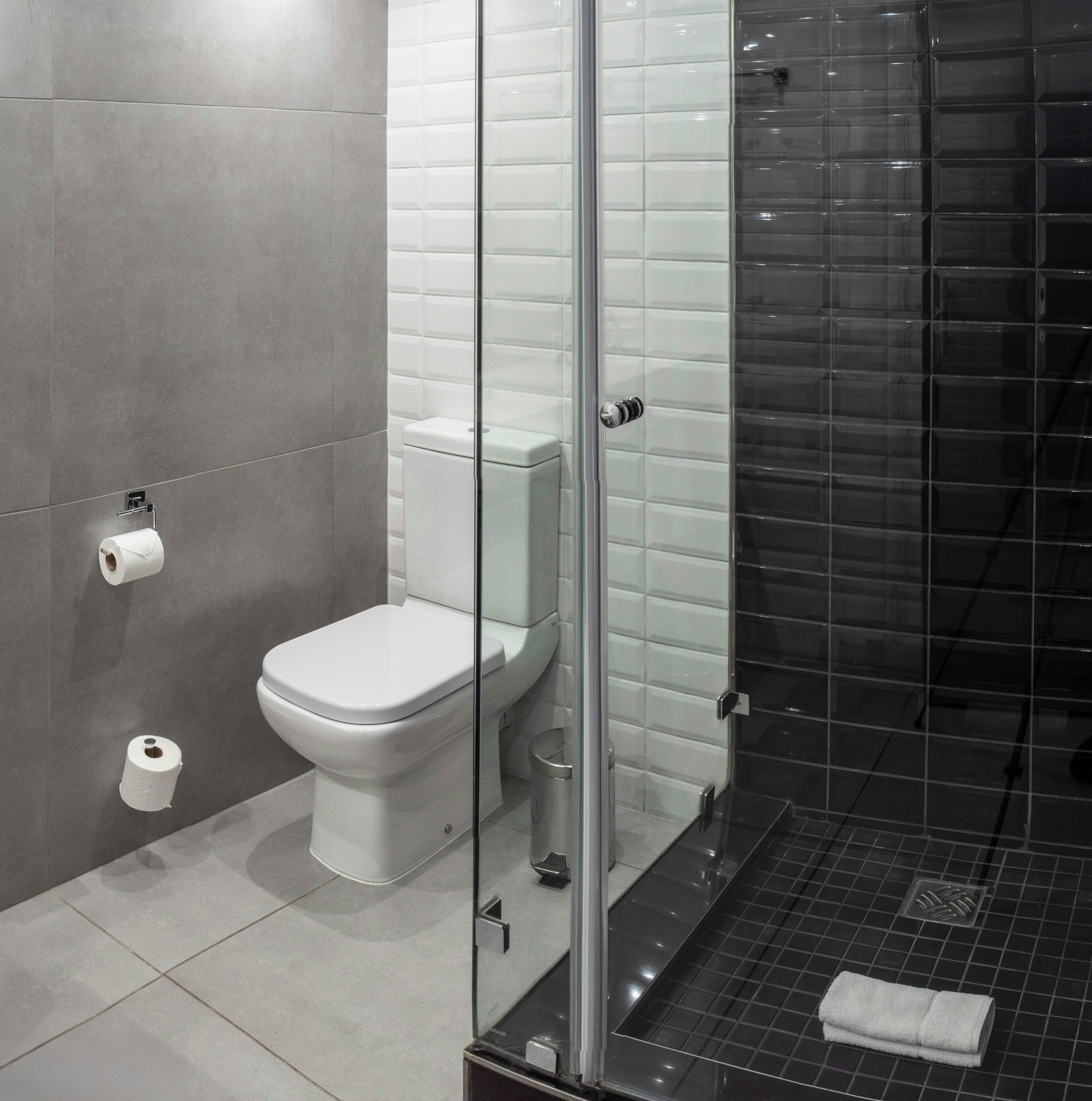 Un baño moderno con inodoro, cabina de ducha de vidrio y un perchero para toallas.