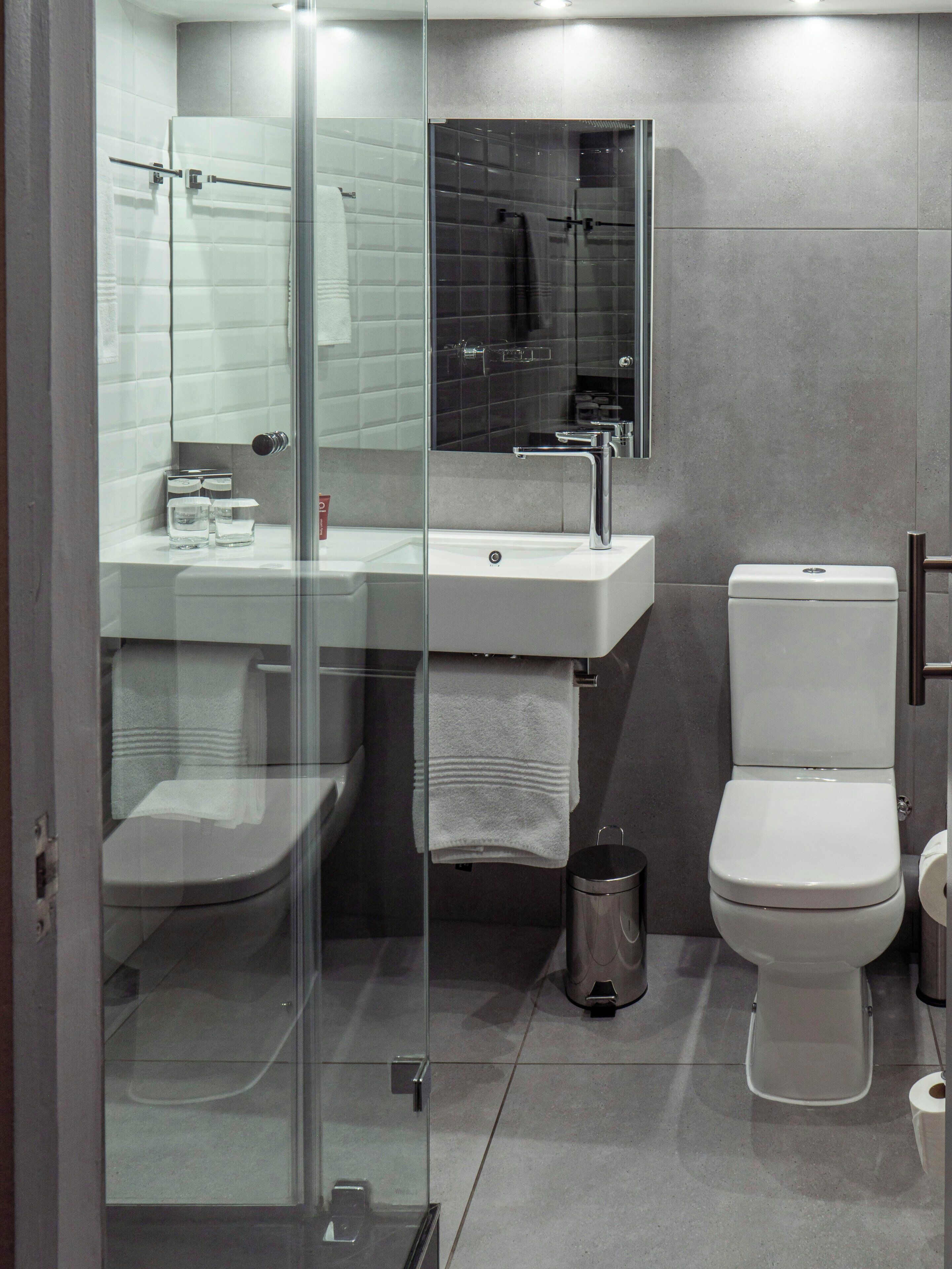 Une salle de bain moderne avec une douche à parois de verre, un lavabo blanc et des toilettes.