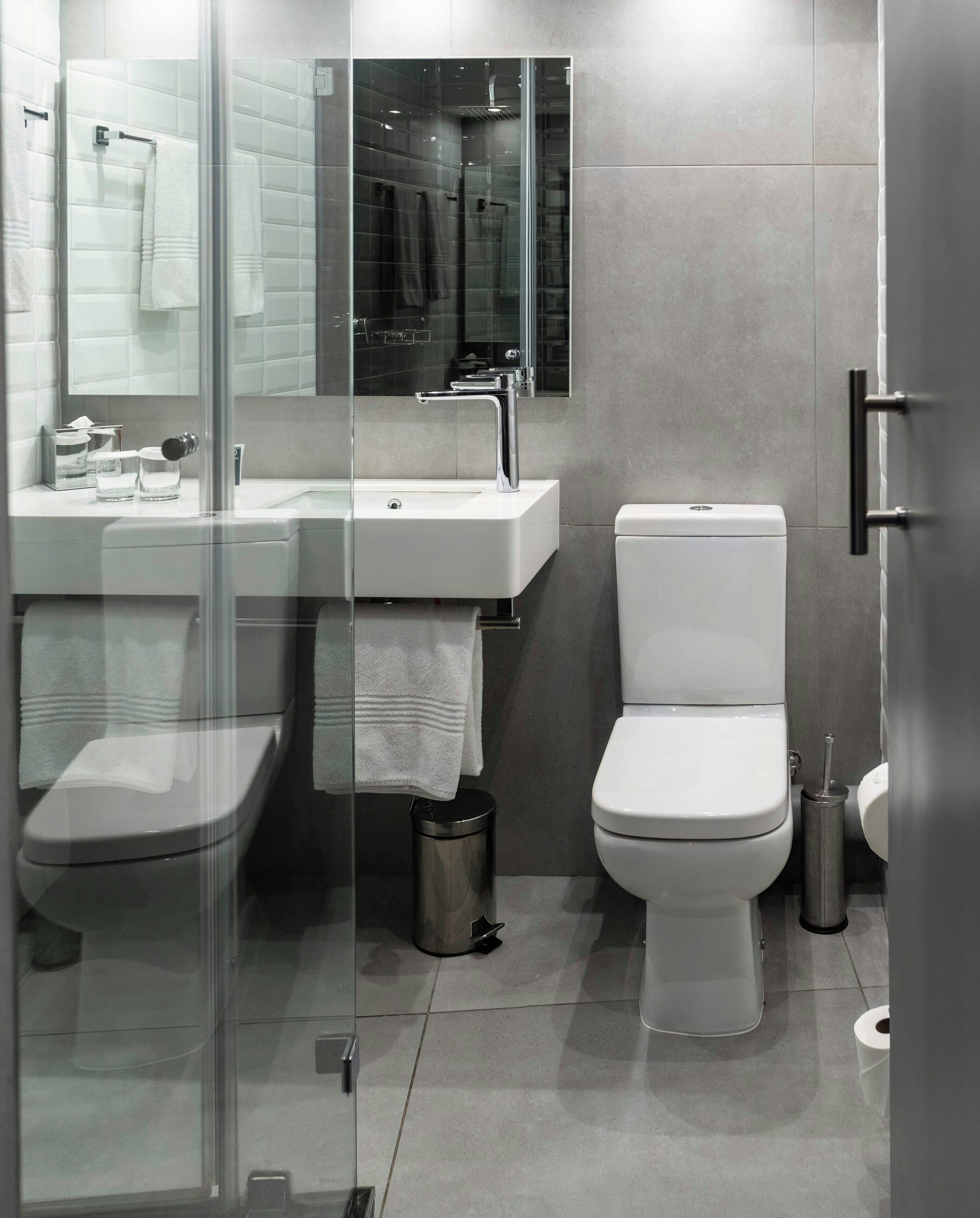 Un baño moderno con cabina de ducha de vidrio, un lavabo blanco y un inodoro.