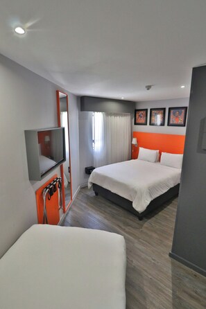 Una habitación de hotel con dos camas, televisión, escritorio y baño.