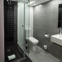 Un baño moderno con ducha envuelta en vidrio, inodoro y lavamanos con espejo.