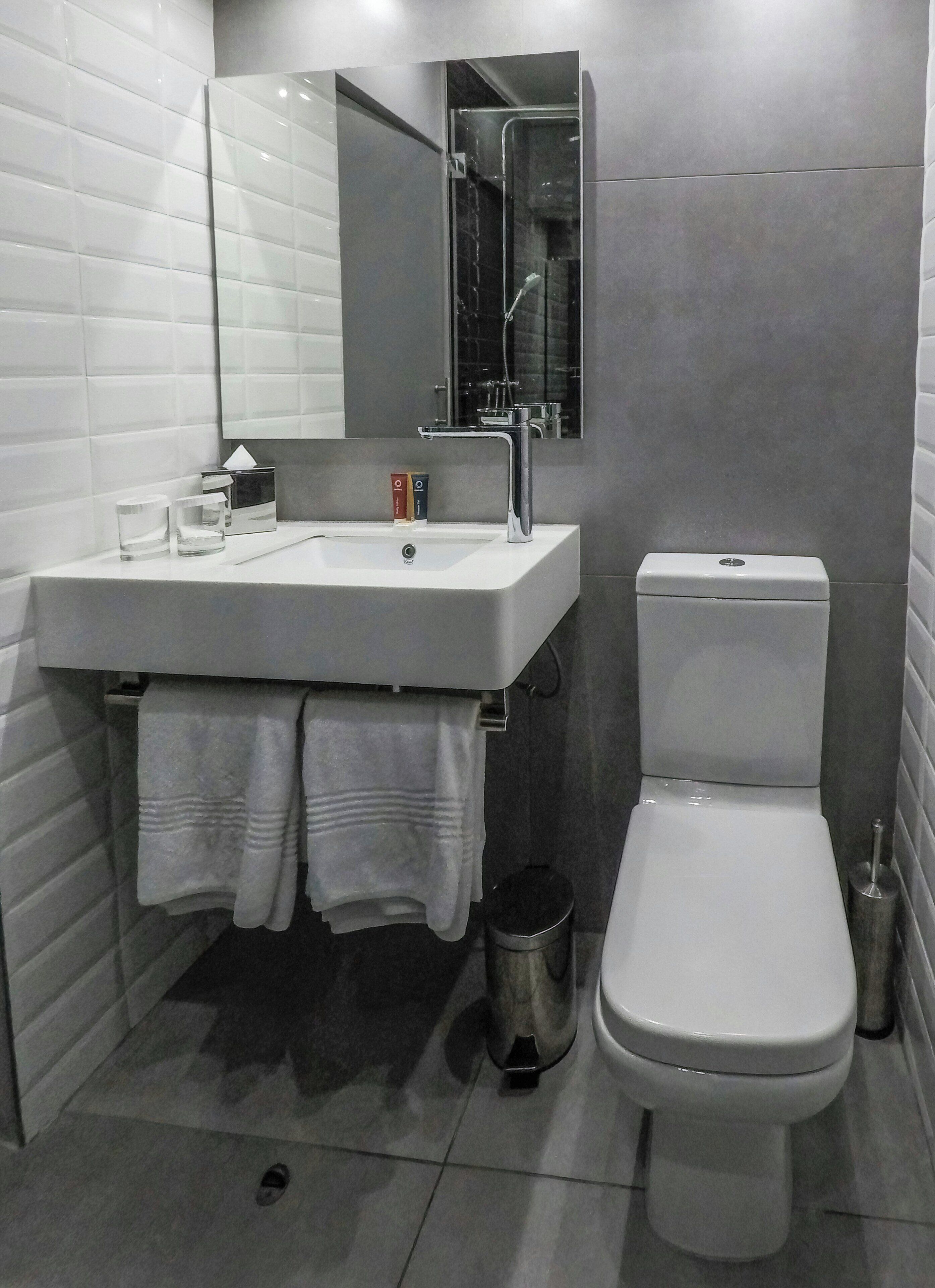 A modern bathroom with a white sink, a toilet, and a mirror above the sink.