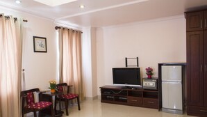 A living room with a TV, a refrigerator, and a dining area with chairs and a table. - Thao Nguyen Apartment (Ho Chi Minh City)