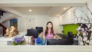 A reception desk with a computer, a decorative golden statue, and a vase of flowers. - Thao Nguyen Apartment (Ho Chi Minh City)