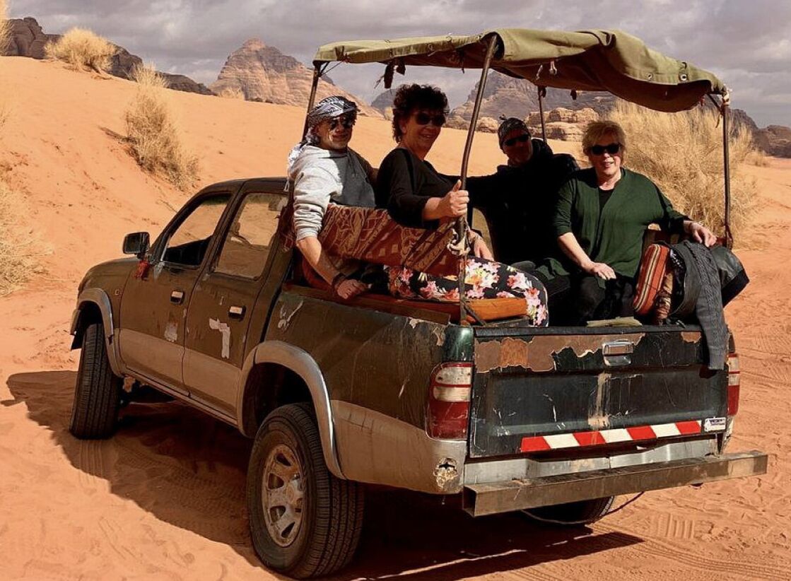 Un véhicule tout-terrain robuste, équipé d’un porte-bagages sur le toit, avec des passagers à bord, dans un décor désertique.