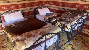 A corner bedroom with two beds, patterned walls, and a tiled floor. - Wadi Rum Sky (Wadi Rum)