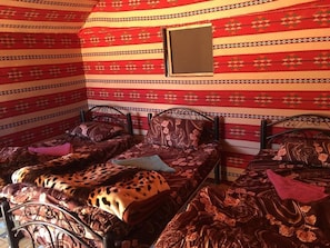 A room with a patterned red and beige wall, a small window, and a metal bed frame with two beds. - Wadi Rum Sky (Wadi Rum)