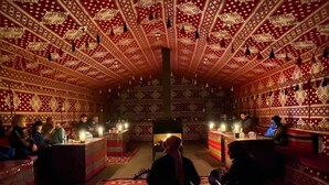 A traditional room with patterned walls and a ceiling, featuring a central area with a low table and chairs. - Wadi Rum Sky (Wadi Rum)