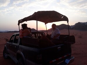 A desert scene with a vehicle and people. - Wadi Rum Sky (Wadi Rum)