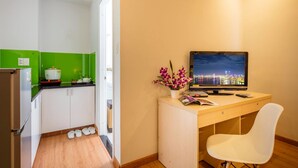 Ein kleines Zimmer mit Küchenzeile, Schreibtisch mit Computer und Stuhl.