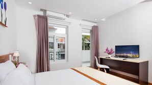 Ein Hotelzimmer mit Bett, Schreibtisch mit Fernseher, Stuhl und einem Fenster mit Vorhängen.