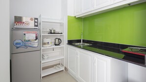Una cocina con armarios blancos, salpicadero verde y un refrigerador Toshiba.