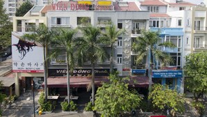 Un edificio de varios pisos con un letrero que dice 'VIEN DONG Hotel' y una clínica de 'Cuidado de la piel y cuerpo'.