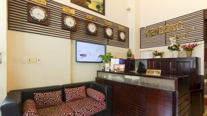 Zona de recepción con relojes mostrando Tokio, Hanói y Seúl, y una pantalla de televisión.