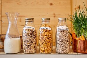 Three glass jars labeled with different types of cereal, a milk bottle, and a potted plant.