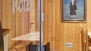 A hotel interior with wooden walls, a glass partition, and a painting of a person. - Hotel Capima (Cologne)