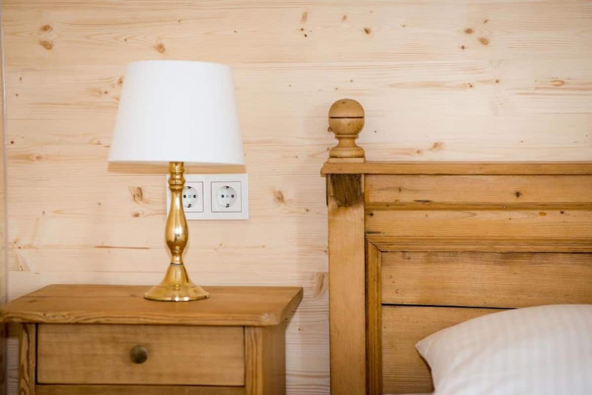 Ein Nachttisch aus Holz mit einer Messinglampe und einer Steckdose.