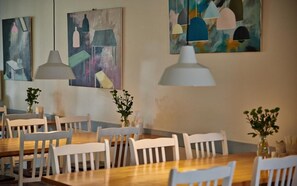 A dining area with wooden tables and white chairs, decorated with potted plants. - Fredensborg Vandrerhjem - Hostel (Fredensborg)