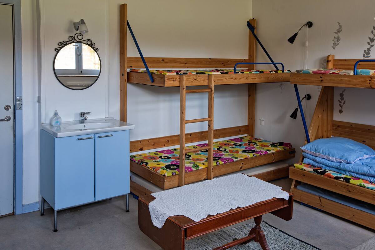 Ein Schlafraum mit Etagenbett, Holzleiter, kleinem Waschbecken und Spiegel.
