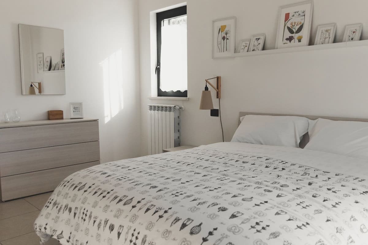 A bedroom with a bed, dresser, and a window.