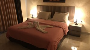 Hotellihuone, jossa on suuri sänky, kaksi yöpöytää ja taulu seinällä.