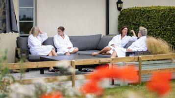 Un groupe de personnes vêtues de longues robes blanches, assises sur un canapé gris placé à l’extérieur.